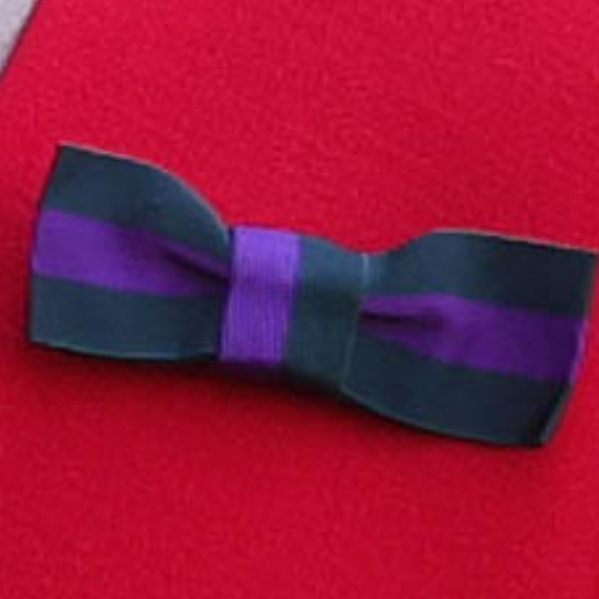 The bow-shaped brooch in Wimbledon's purple and green pinned to Kate's red dress